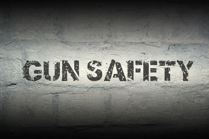 gun safety stencil print on the grunge white brick wall; specially designed font is used